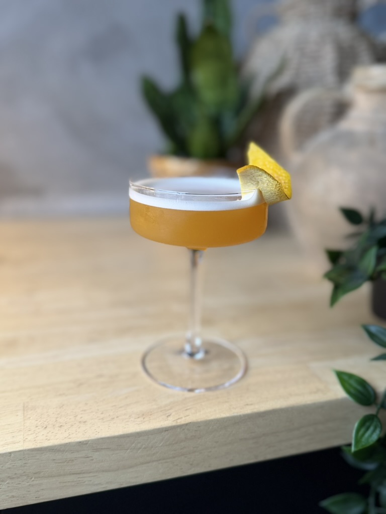 A golden Mystic cocktail with a citrus garnish, waiting for the event organizer