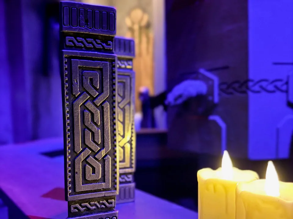Blue-lit metal puzzle objects beside glowing candles inside The Tears of Freya